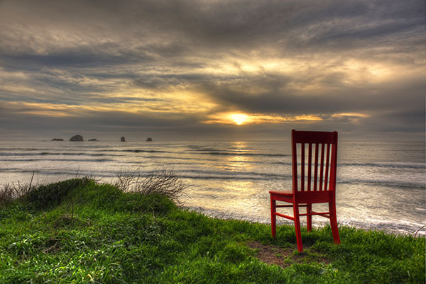 Photo Red Chair looking at sunset over ocean