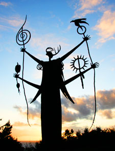 Photo of Shaman of the Benediction sculpture silhouetted against sunset